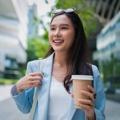 Individual holding a coffee cup outdoors.