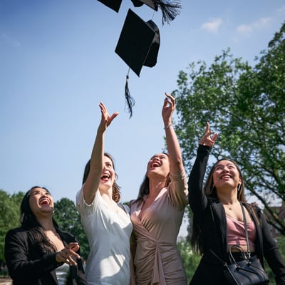 Group of individuals throwing their graduation caps in the air.