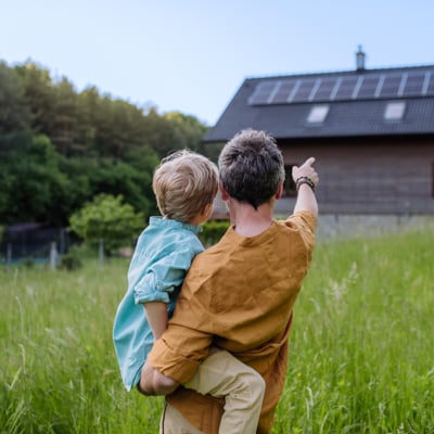Individual and their child looking at a house with solar panels.